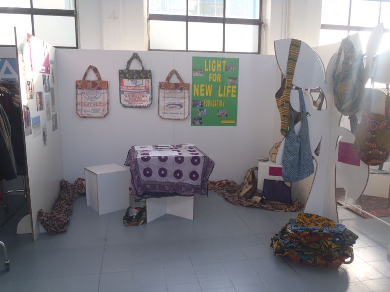 Our stand at Change-up in Milan: Bumbuli bags on the wall beside a green Light for New Life sign