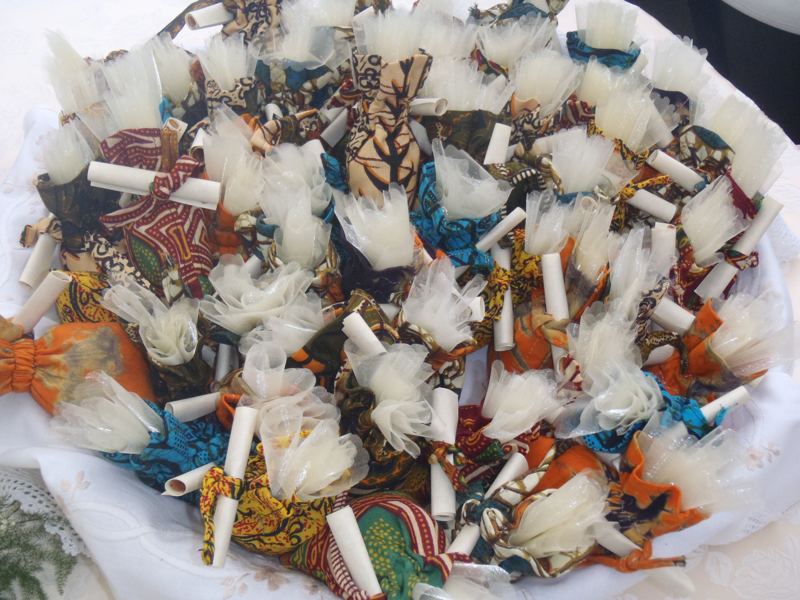 Dozens of small wedding favours wrapped in bright kitenge cloth and white ribbon